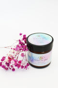 Brown glass candle with holographic sticker branding, with pink flowers on a white background